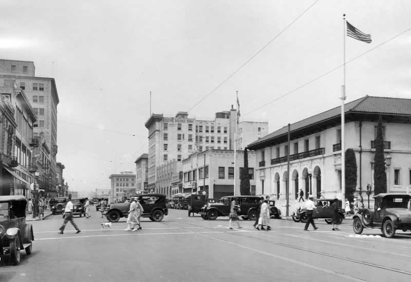 An old white and black photo of predestrians and old cars