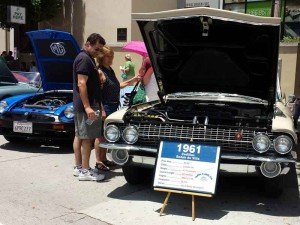 a family inspects a vintage car from 1961