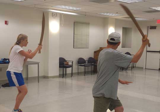two people holding wooden swords