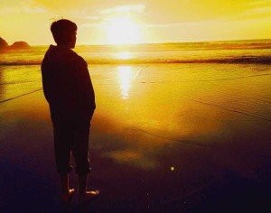 A man standing by the beach at sunset