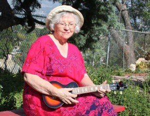 a woman in a white hat and a pink dress with mandolin