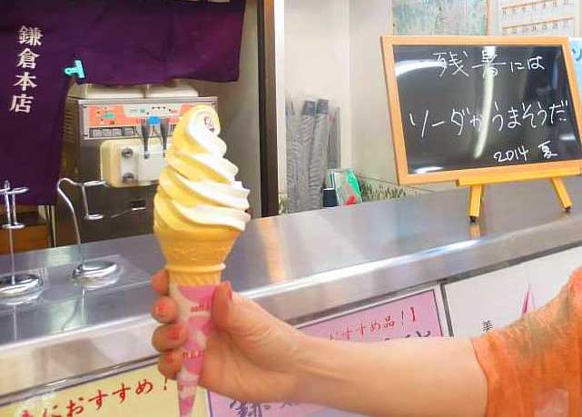 A hand holding a cone of vanilla ice cream