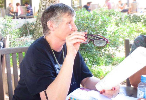 A woman holding her glasses and reading a book