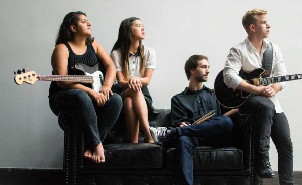 Four musicians holding instruments and staring off into the distance