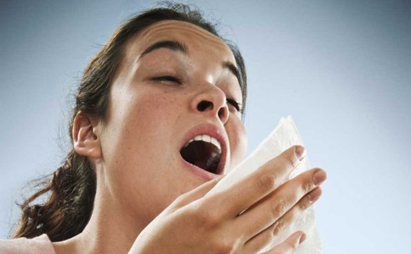 A woman covering mouth as she sneezes