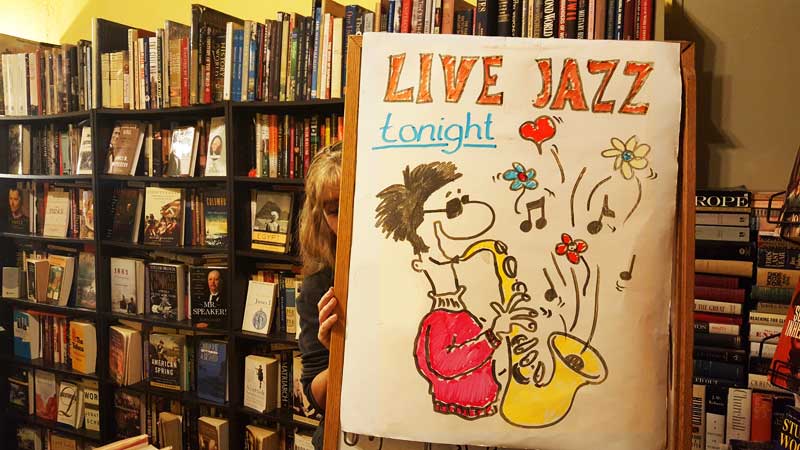 A woamn adjustsa sign advertsing Live Jazz