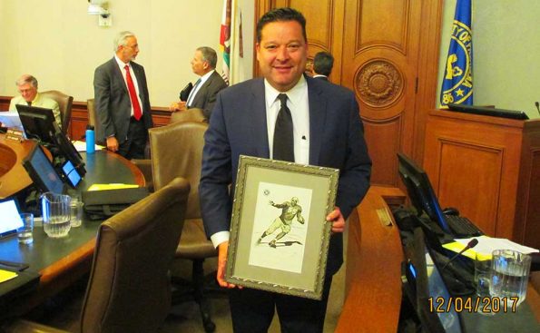 Councilmember Victor Gordo holding a poster of the statue of Jackie Robinson (Photo - Garrett Rowlan).