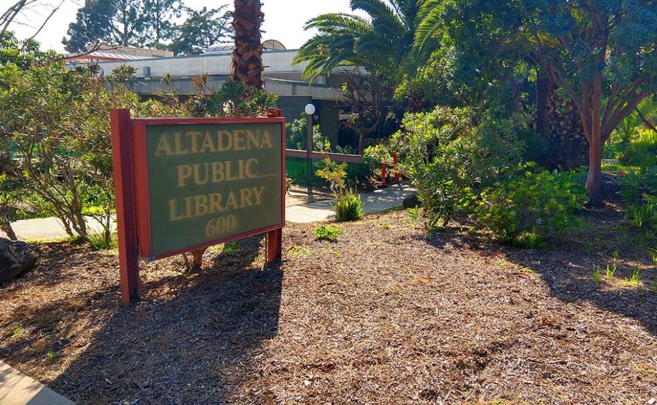 A sign of the Altadena Library next to grass