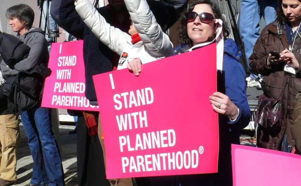 Women supporting PLanned Parenthood on the street with signs in Pink color