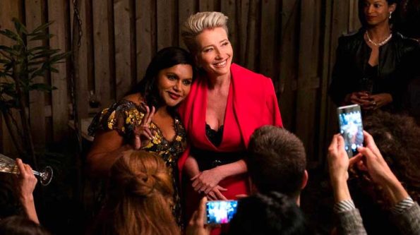 a lasy in a red blazer is hugging an indian looking lady in a dark dress in front of the press