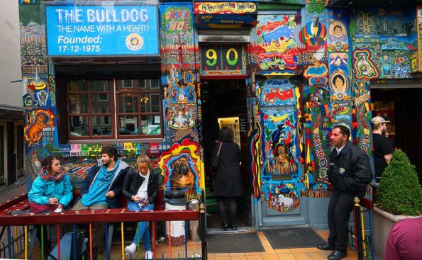 Young people and one older person hanging outside a shop with corful graffiti art