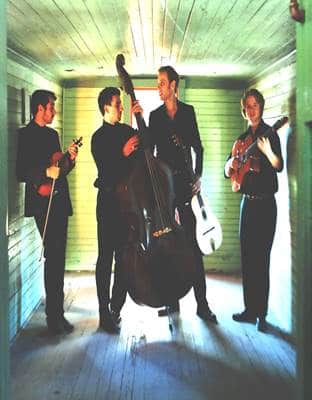 4 band members with lighting coming from behind them