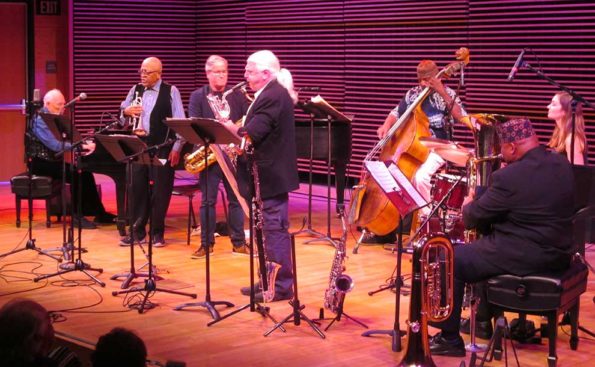 A group of musicians with purpllish lighting playing music