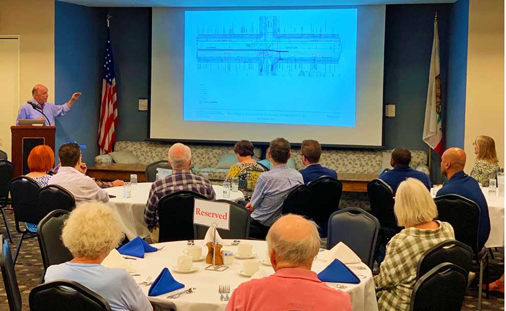 A man speaking at the podium with people attending ina large room