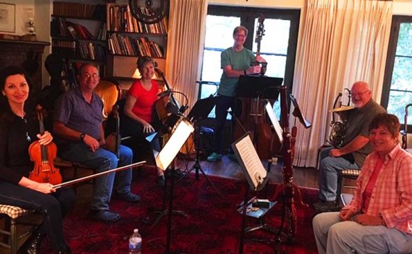 Musicians gathered in a living room with their instruments