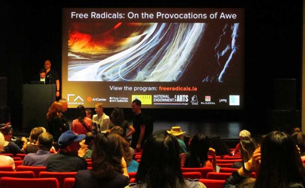 A screen and attendees and a panel on stage