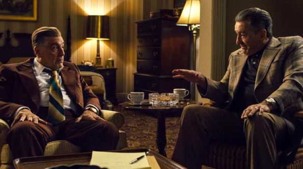 two men in suits talking to each other in a fancy home