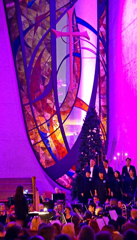 A long stained glass window lit in purple and red