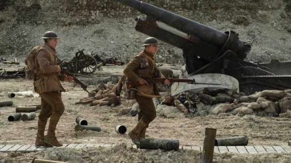 two soldiers pass a destroyed tanker