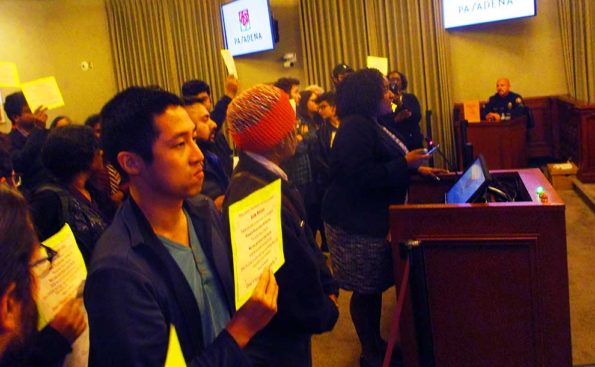 tenants and residents hold signs and an african american person addresses the council