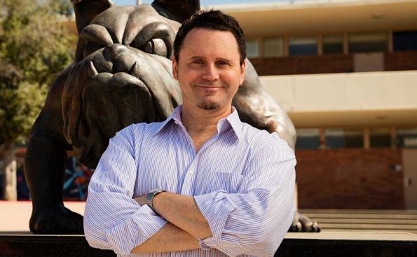 A man crossing his hands and smiling at the camera