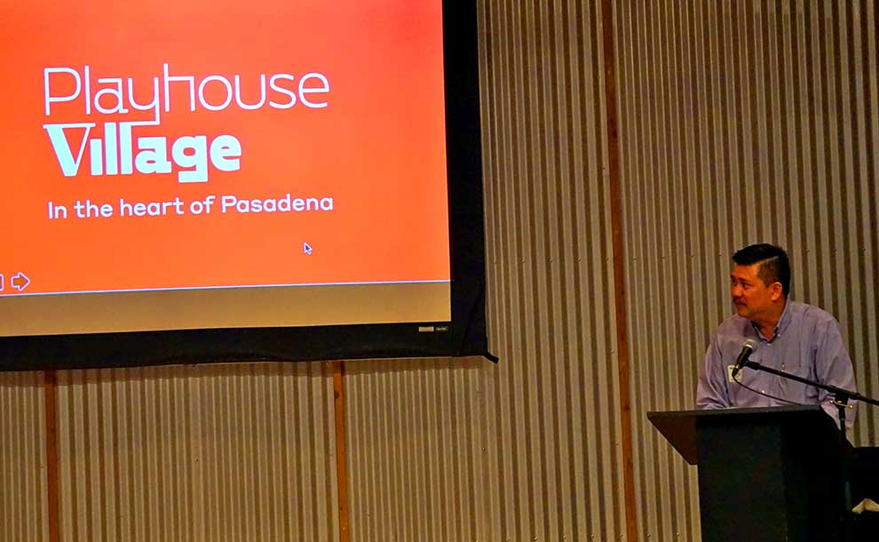 A man on a podium with a projected sign in orange colors
