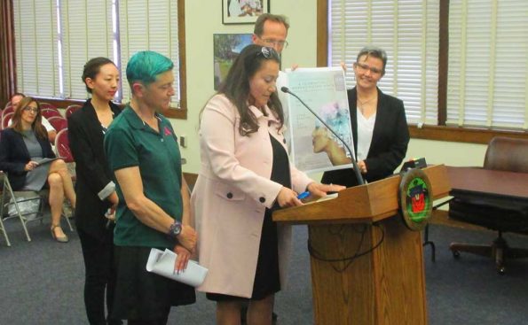 A woman speaker with a male student with green colored hair introduce a poster