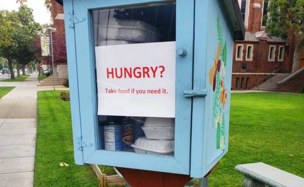 A sign on a snall library asking if hungry take food from inside