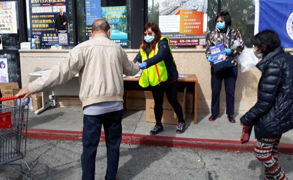 a man reaches out to take a mask from a lady wearing a mask