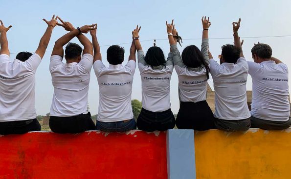Staff raising their hands sitting on a color painted wall