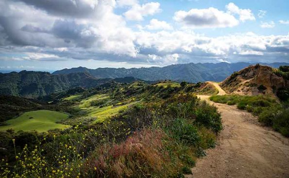 A dirt trail with clous and sunny sky