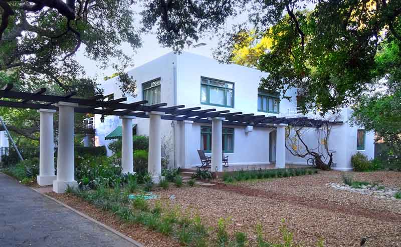 A squared house with terraces and greenery in the front