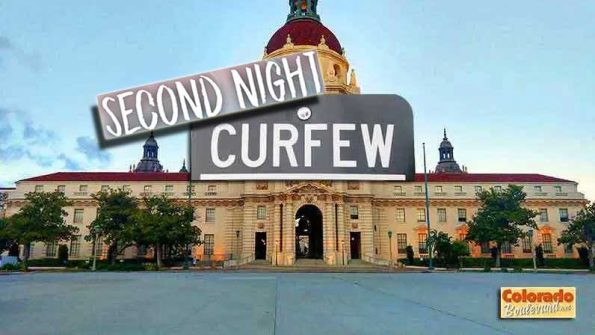 a 2nd night curfew sign on top of a buidling
