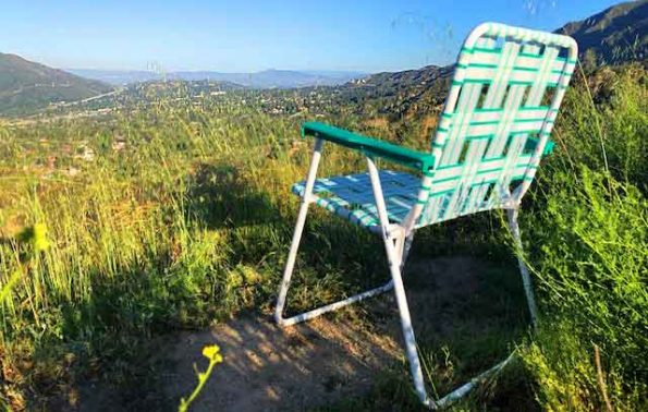 A lawn chair on a grassy hill overlooking a view of the city