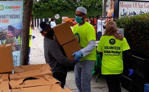 people dressed in yellow shirts moving bozes full of food
