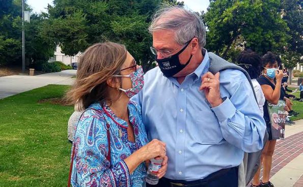 A white haired man with a woman next to him, both with masks