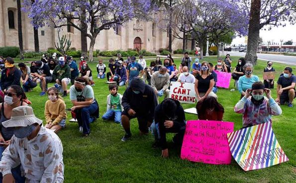 young students and adlts kneel on the grass