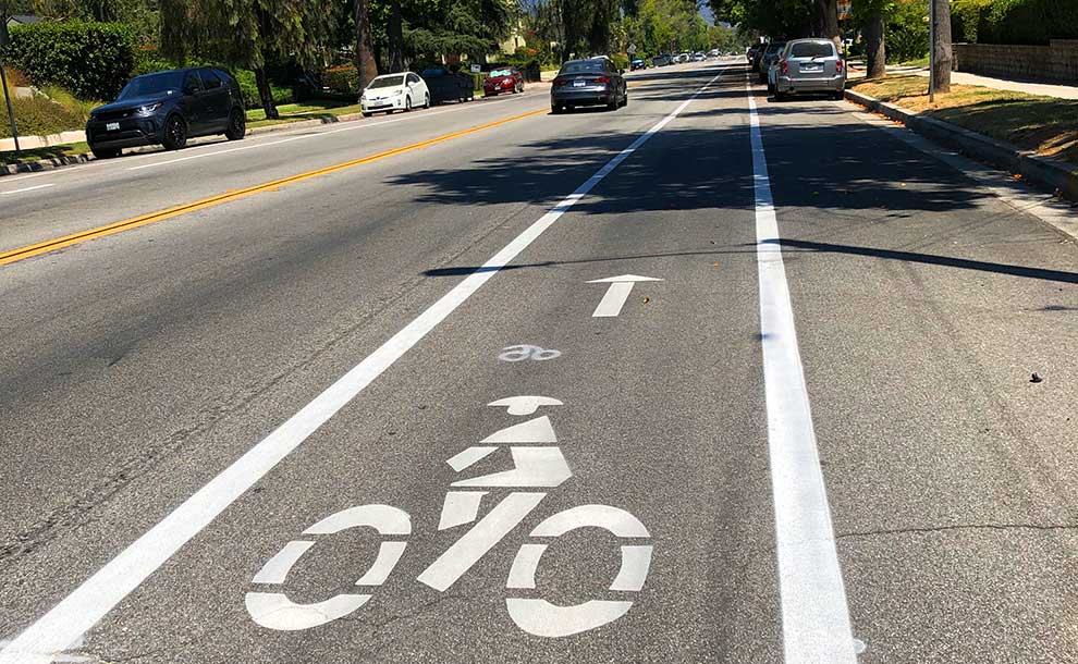 A car on the street next to markings of a bike lane