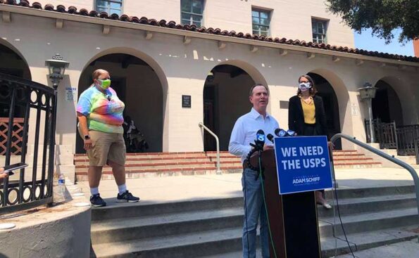 A man on steps of a building with arches flanked by two women on the steps behind him
