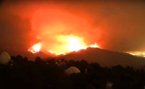 flames raging at night with hills in silhouette