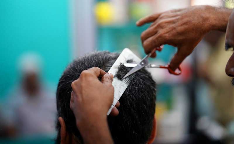 two hands with cissors and a comb cutting hair