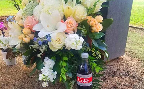 memorial flowers next to a bottle of diet coke