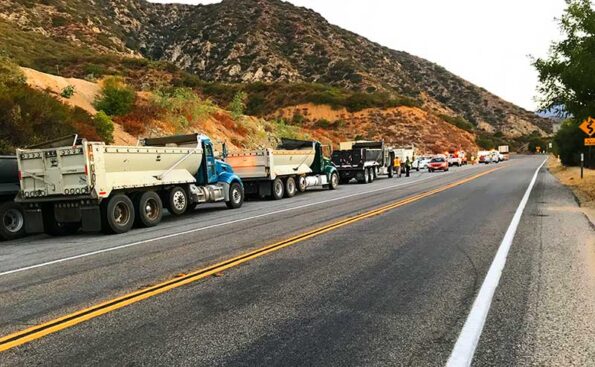 lines of trucks on the side of the road and a kia n the middle