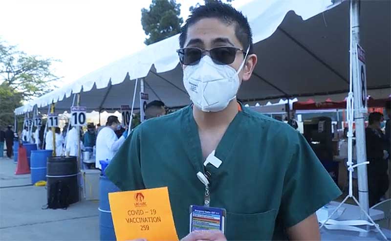 RN standing in front of a tent with healthcare workers lining up behind him