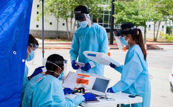 men and women in lab coats under a tent