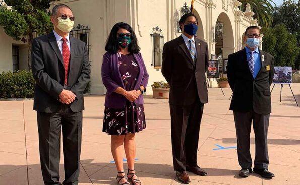 3 men and one woman standing next to each other