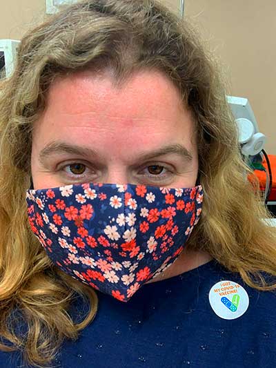 a woman with a mask on and a sticker on her shirt