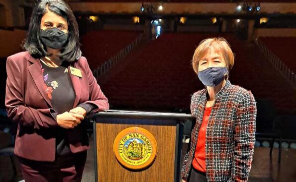 Two women standium next to a podium