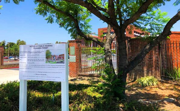 A sign advertising a meeting next to a gate