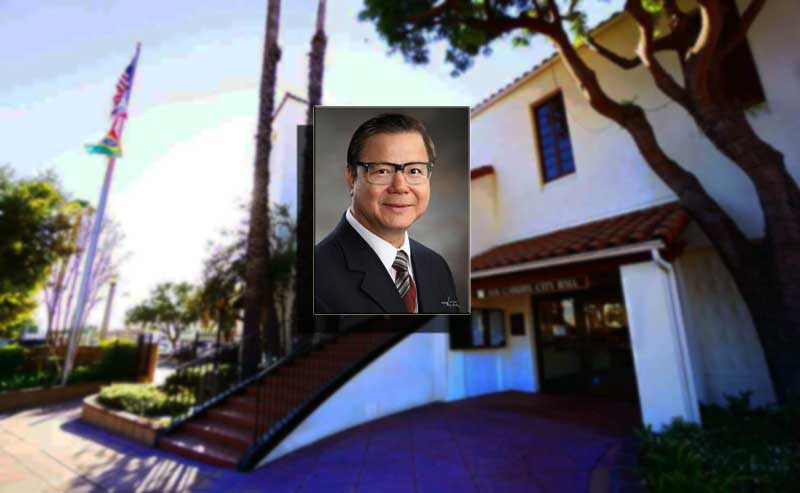 A man with glasses photo over a building of city hall